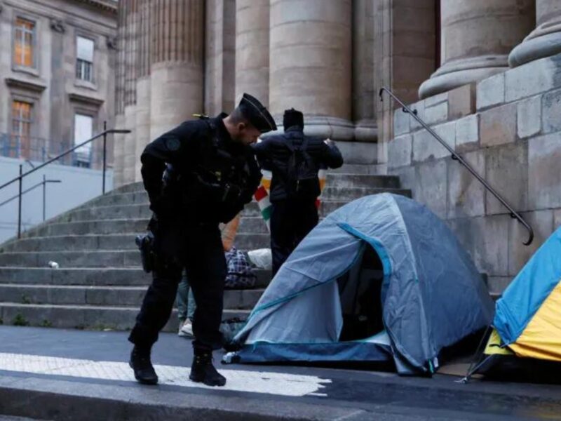 French police officer looks at a migrant tent on Place Saint-Gervais near Paris City Hall, France