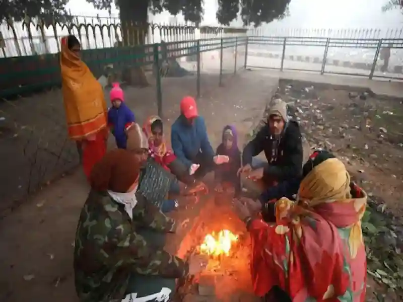 A group of people sit next to a bonfire on a chilly morning in Delhi.